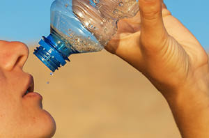 Close-up of a person drinking water outdoors in summer.