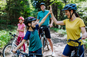 Child wearing a helmet riding a bike in summer.